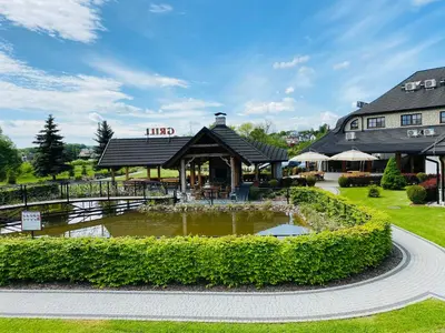 a hotel with a pond in front of a building at Hotel Tadeusz in Uszew