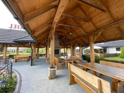 a large wooden pavilion with benches and tables at Hotel Tadeusz in Uszew