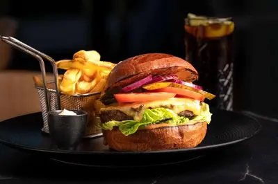 a sandwich on a plate with a basket of fries at Park Inn by Radisson Krakow in Kraków