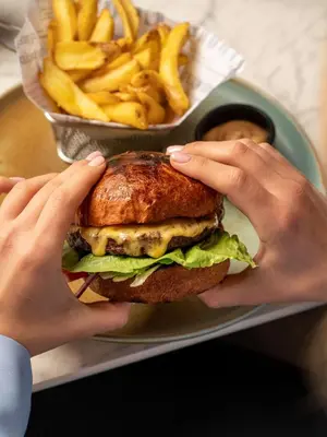 a person holding a sandwich and french fries at Park Inn by Radisson Krakow in Kraków