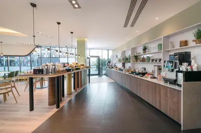 a restaurant with a long counter with tables and chairs at Park Inn by Radisson Krakow in Kraków