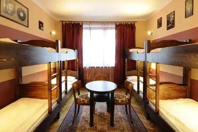 a room with four bunk beds and a table and chair at Hostel Deco in Kraków