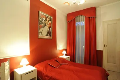 a bedroom with a red bed and red curtains at Hostel Deco in Kraków
