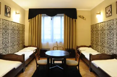 a room with four beds and a table and a window at Hostel Deco in Kraków