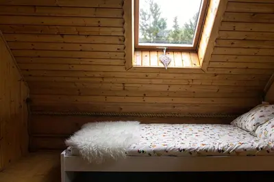 a bed in a wooden room with a window at CHATA PACHNĄCA LASEM in Andrychów