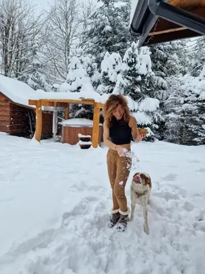 a woman standing in the snow with a dog at CHATA PACHNĄCA LASEM in Andrychów