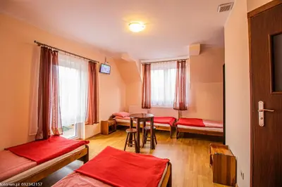a room with beds and a table and chairs at Dom Wypoczynkowy Modrys in Zawoja