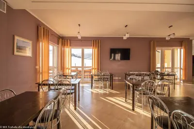 a dining room with tables and chairs and a television at Dom Wypoczynkowy Modrys in Zawoja
