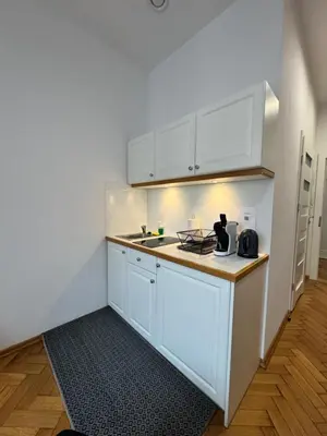 a kitchen with white cabinets and a table at Memory Apartments in Kraków