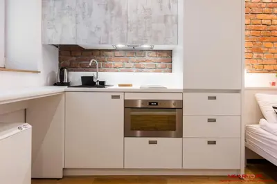 a kitchen with white cabinets and a brick wall at Old Town Topolowa 48 in Kraków