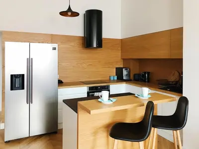 a kitchen with a white refrigerator and two chairs at TCF Home - Big Apartment with Free Garage in Kraków
