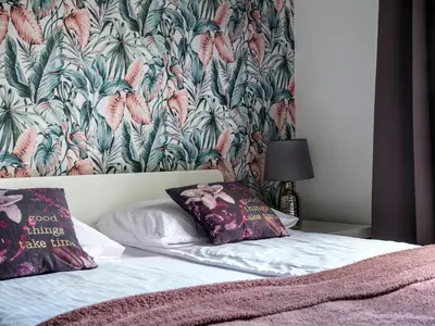 a bed with two pillows on it with a floral wallpaper at CracWoW VIP Apartment in Kraków
