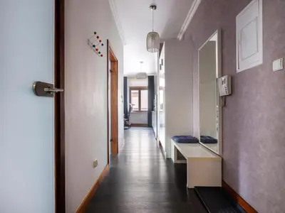 a hallway leading to a room with white walls and wooden floors at CracWoW VIP Apartment in Kraków