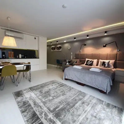 a bedroom with a bed and a desk and a kitchen at Studio Łazarza 13 in Kraków