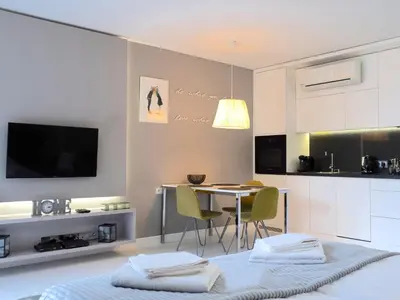 a living room with a table and a kitchen at Studio Łazarza 13 in Kraków