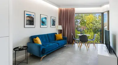 a living room with a blue couch and a table at MY KRAKOW Apartments - Rakowicka in Kraków