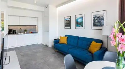 a living room with a blue couch and yellow pillows at MY KRAKOW Apartments - Rakowicka in Kraków