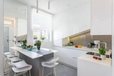 a kitchen with white cabinets and white stools at MY KRAKOW Apartments - Rakowicka in Kraków