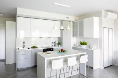 a kitchen with white cabinets and a counter with stools at MY KRAKOW Apartments - Rakowicka in Kraków