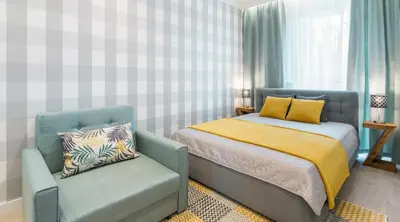 a bedroom with a bed and a blue chair at MY KRAKOW Apartments - Rakowicka in Kraków