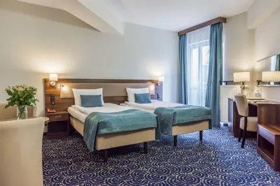 a hotel room with a bed and a desk at Hotel Justyna in Kraków