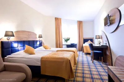 a hotel room with two beds and a desk at Hotel Justyna in Kraków