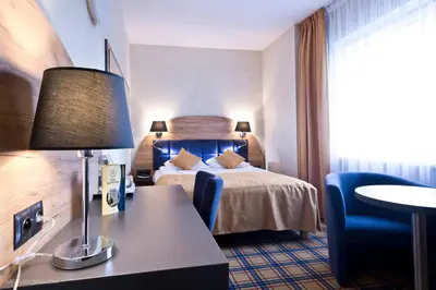 a hotel room with a bed and a desk with a lamp at Hotel Justyna in Kraków