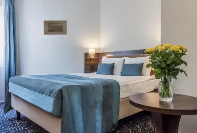 a bedroom with a bed with a vase of flowers on a table at Hotel Justyna in Kraków