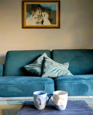 a blue couch with two cups on a table at Friedleina 7 Kamienica Prezydencka in Kraków