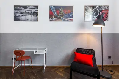 a room with a chair and a desk with a red pillow at Friendhouse Apartments Starovislna in Kraków