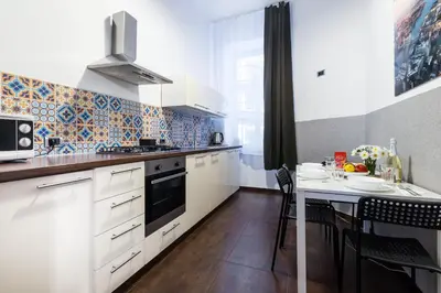 a kitchen with white cabinets and a table with chairs at Friendhouse Apartments Starovislna in Kraków