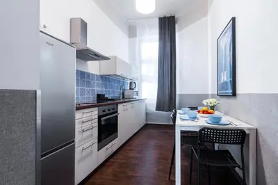 a kitchen with white cabinets and a counter with a table at Friendhouse Apartments Starovislna in Kraków