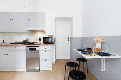 a kitchen with white cabinets and a counter with stools at Friendhouse Apartments Starovislna in Kraków