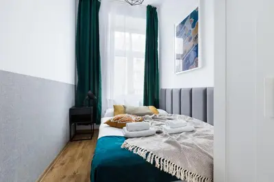 a bedroom with a bed with green curtains at Friendhouse Apartments Starovislna in Kraków
