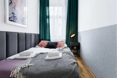 a bedroom with a large bed with green curtains at Friendhouse Apartments Starovislna in Kraków