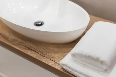 a white bathroom sink on a wooden tray with towels at City of the Kings - Inca Apartment in Kraków