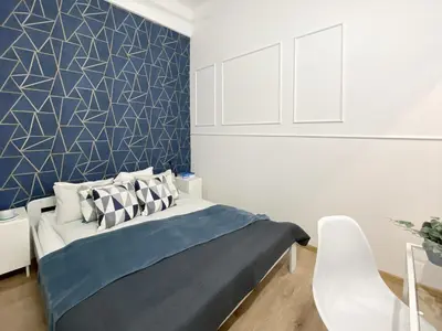 a bedroom with a bed with a blue wall at GREEN APARTMENTS #Kazimierz, building B in Kraków