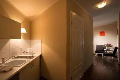 a kitchen with a sink and a door to a room at Leone Aparthotel in Kraków