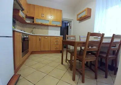 a kitchen with a wooden table and chairs and a kitchen with a sink at Apartament Oficyna in Kraków