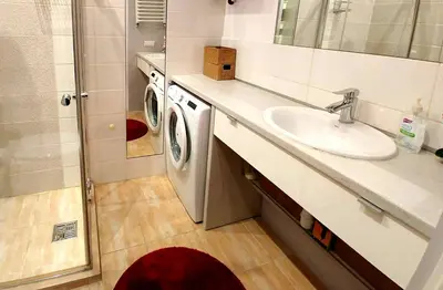 a bathroom with a sink and a washing machine at Apartament Oficyna in Kraków