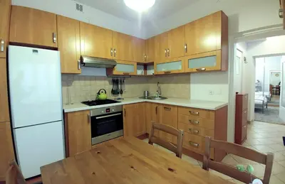a kitchen with wooden cabinets and a white refrigerator at Apartament Oficyna in Kraków
