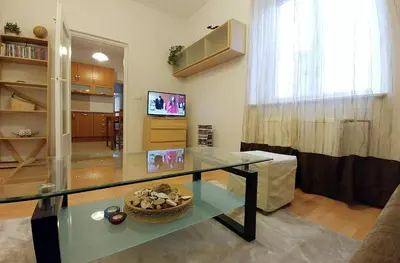 a living room with a glass table and a television at Apartament Oficyna in Kraków