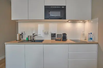 a kitchen with white cabinets and a sink and a microwave at RAJSKA 3 by PI Apartments in Kraków