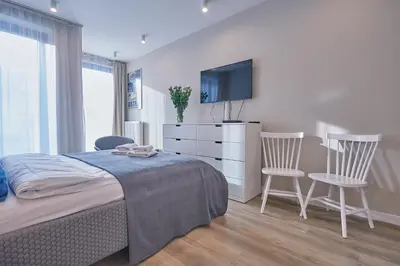 a bedroom with a bed and a tv and two chairs at RAJSKA 3 by PI Apartments in Kraków