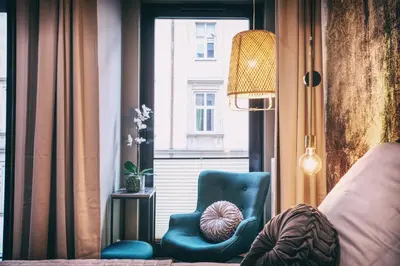 a bedroom with a blue chair and a window at RAJSKA 3 by PI Apartments in Kraków