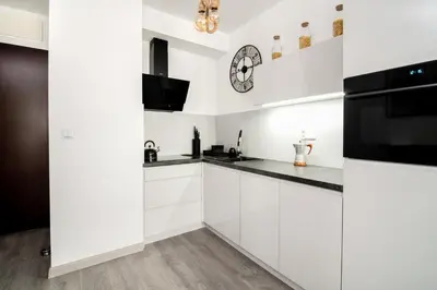 a kitchen with white cabinets and a clock on the wall at Unique apt EVE - free garage in Kraków