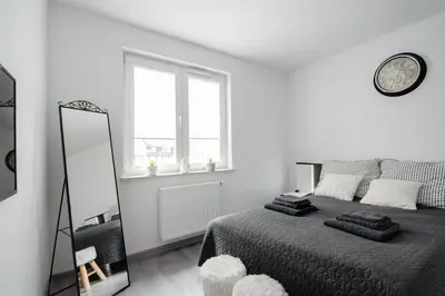 a white bedroom with a bed and a mirror at Unique apt EVE - free garage in Kraków