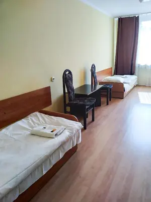 a hotel room with two beds and a table and chairs at CKS Kraków (Centrum Konferencyjno-Szkoleniowe CS Natura Tour) in Kraków