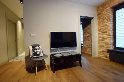 a living room with a tv and a chair at Jewish Quarter Comfort - In City Apartments in Kraków