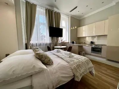 a bedroom with a bed with pillows and a kitchen at Tresor Barska Apartments in Kraków